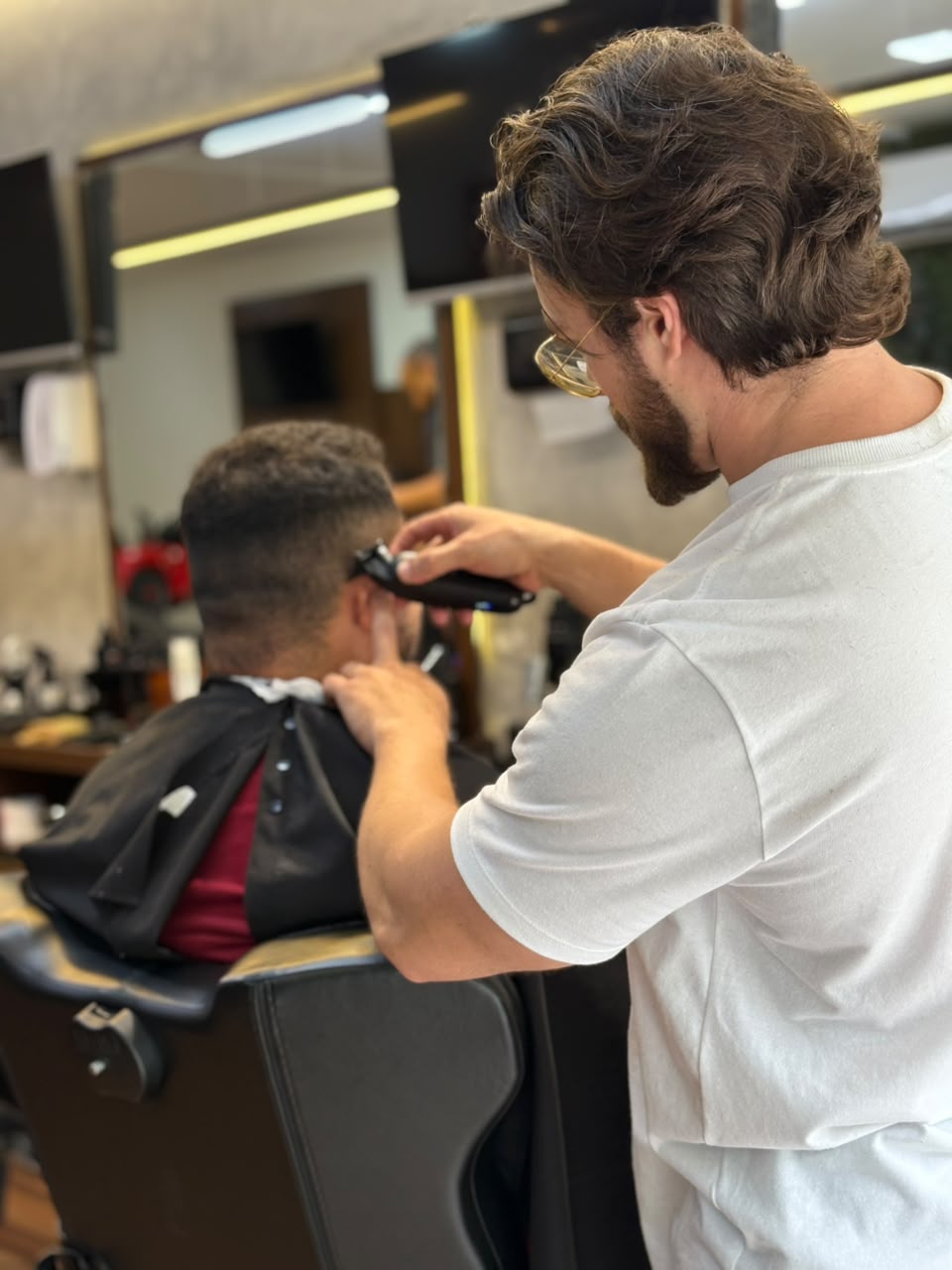 Barbeiro fazendo acabamento com máquina na nuca do cliente